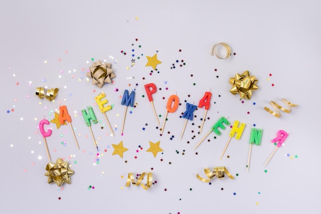 Bunte Kerzen in den Buchstaben, die alles Gute zum Geburtstag und Goldkonfetti auf blauem Hintergrund-Draufsicht-Horizontal sagen