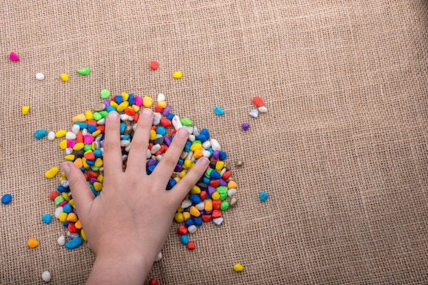 Bunte kleine Kieselsteine in der Hand und auf dem Boden