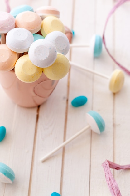 Bunte Lolli Pops und blaue Gummibärchen in einer rosa Tasse