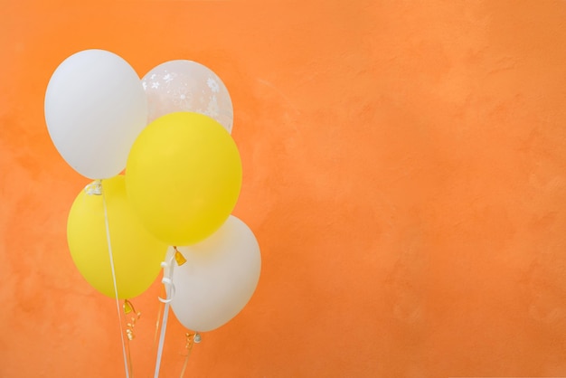 Bunte Luftballons auf orangefarbenem Wandhintergrund