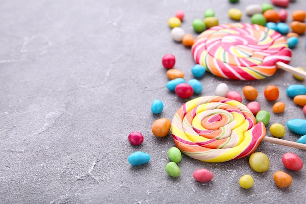 Bunte Lutscher und unterschiedliche farbige runde Süßigkeit auf grauem Hintergrund