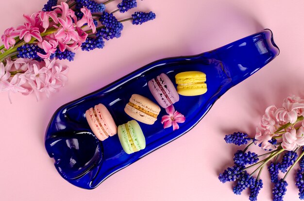 Bunte macarons auf blauer Umhüllungsplatte auf Pastellrosa