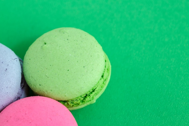 Bunte macarons oder Makronenplätzchen auf grünem Hintergrund