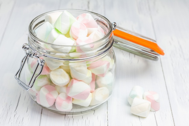 Bunte Marshmallows im Glasglas auf heller hölzerner Hintergrundnahaufnahme