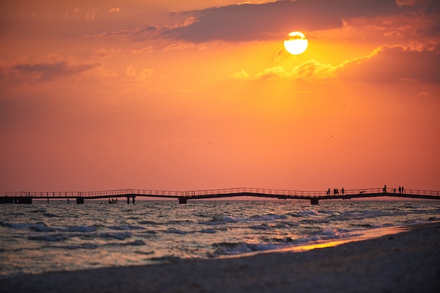 Bunte Morgendämmerung über dem Meer. Pier am Horizont.