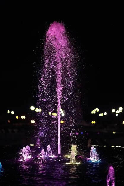 bunte Nachtfontänen / farbige Wasserstrahlen in einem Springbrunnen, Nachtbeleuchtung in der Stadt, touristische Objektkunst