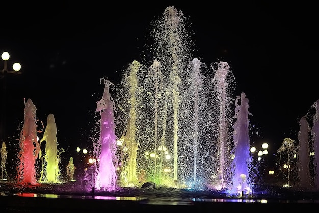 bunte Nachtfontänen / farbige Wasserstrahlen in einem Springbrunnen, Nachtbeleuchtung in der Stadt, touristische Objektkunst