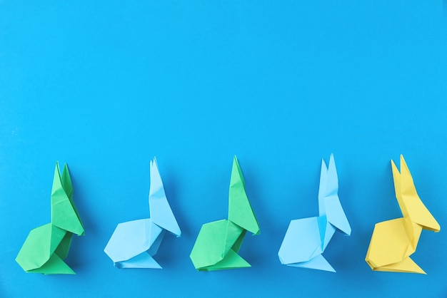 Bunte Origami-Osterkaninchen des Papiers auf Blau