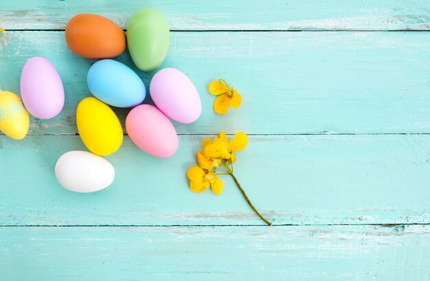 Bunte Ostereier im Nest mit Blume auf rustikalem hölzernem Plankenhintergrund