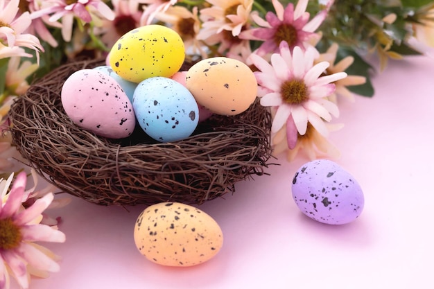 Bunte Ostereier im Nest und Blumen auf rosa Hintergrund mit Kopienraum. Flach liegen.