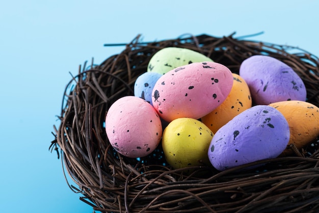 Bunte Ostereier in einem Nest auf blauem Hintergrund