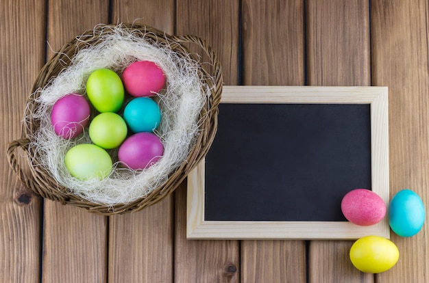 Bunte Ostereier in einem Nest neben einer Tafel