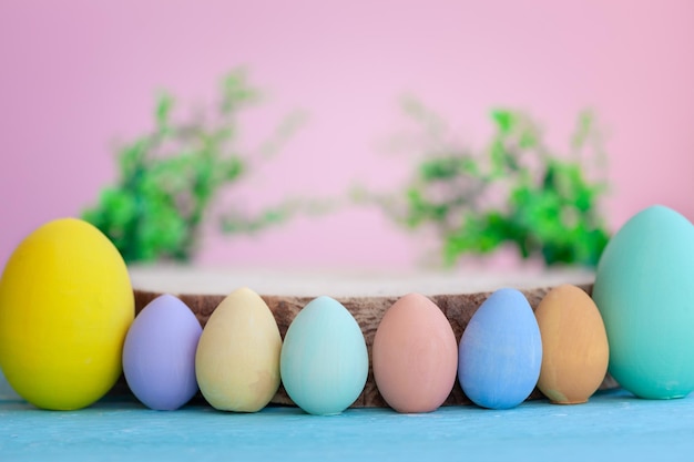 Bunte Ostereier mit leerer Holzplattform auf rosa Hintergrund Osterferien-Mockup-Platz für die Produktpräsentation