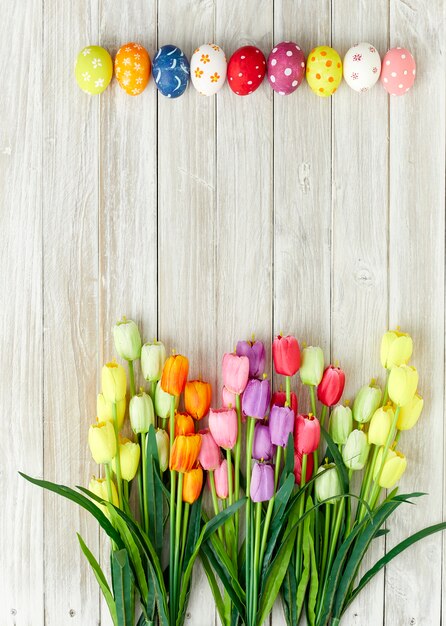 Bunte Ostereier und Tulpen auf Holz