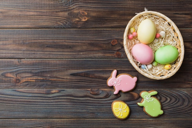 Bunte Osterplätzchen im Korb mit Multi-Farben-Ostereier auf farbigem Hintergrund Pastellfarbene Ostereier Urlaubskonzept mit Kopierbereich