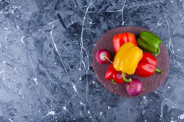 Bunte Paprika, Zwiebel und roter Rettich auf Holzstück.