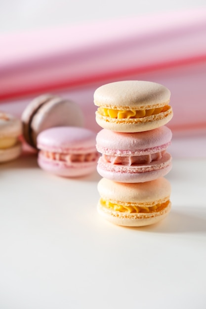 Bunte pastellfarbene französische Makronen oder Macarons auf weißem und rosa Hintergrund