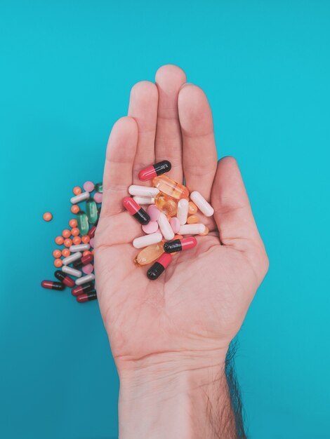 bunte Pillen in der Hand auf blauem Hintergrund