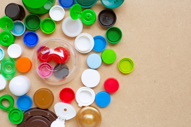 Bunte Plastikflaschenkapseln und Plastikglasdeckel auf Sperrholz