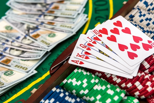 Bunte Pokerchips mit amerikanischen Dollars in der Holzkiste auf grünem Spieltisch.