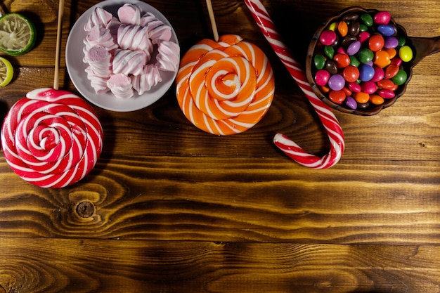 Bunte Pralinen Lutscher Zuckerstange und Marshmallows auf Holztisch