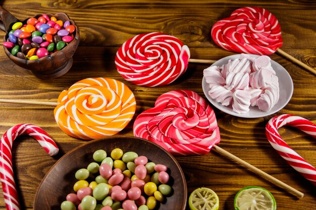 Bunte pralinen lutscher zuckerstange und marshmallows auf holztisch