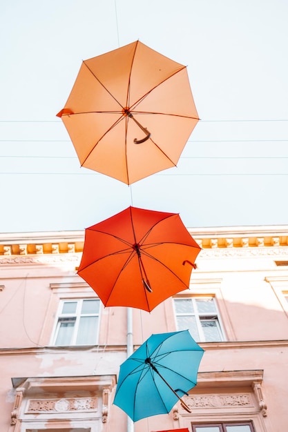 Bunte Regenschirme als Festivaldekoration im städtischen Stadtzentrum von Lemberg. Gelbe, rote, blaue und rote Regenschirme auf Himmelshintergrund.