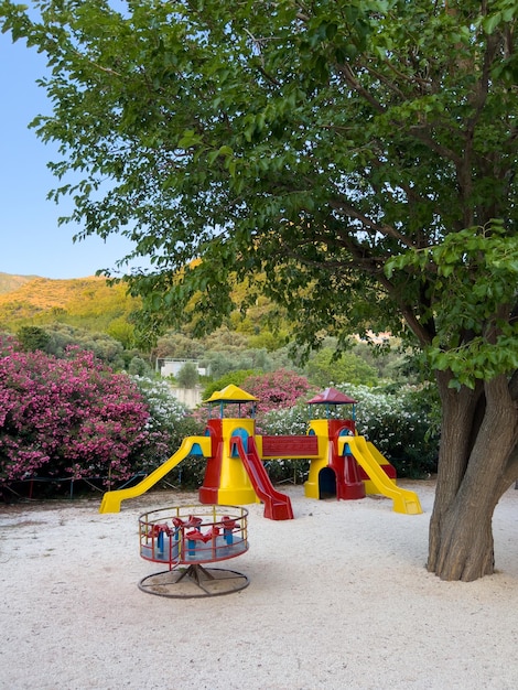 Bunte Rutschen mit Übergängen in Form einer Burg neben dem Karussell stehen auf einem Spielplatz