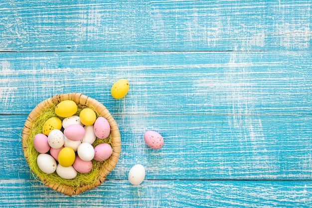 Bunte Schokoladeneier zu Ostern auf blauem Holzhintergrund, Draufsicht, Kopierraum