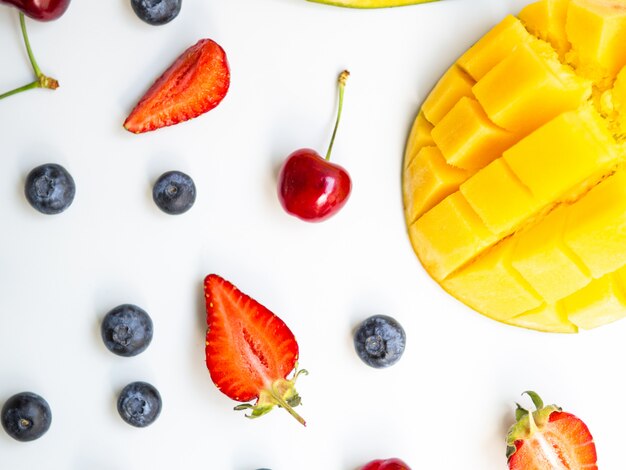 Bunte Sommerfrüchte der Draufsicht. Flache Lage mit Mango, Erdbeere und Kirsche auf weißem Hintergrund