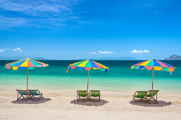 Bunte Strandstühle mit Regenschirmen an einem sonnigen Tag