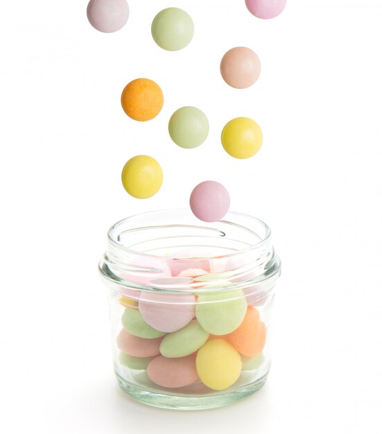 Bunte Süßigkeiten, die in das Glas lokalisiert auf weißem Hintergrund fallen.