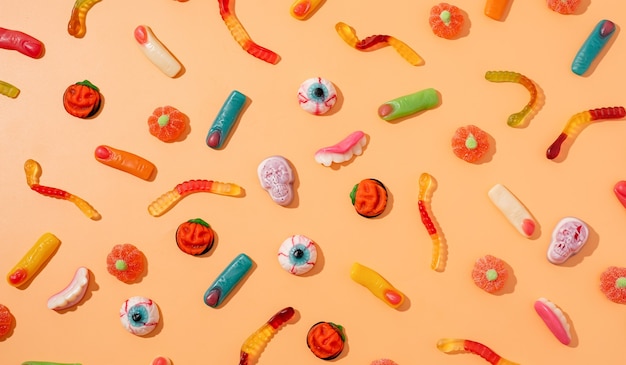 Bunte Süßigkeiten für Halloween-Party auf orangem Hintergrund, Ansicht von oben