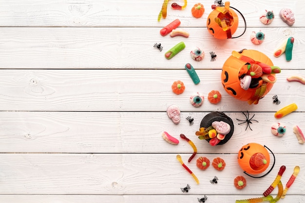 Foto bunte süßigkeiten für halloween-party auf weißem holzhintergrund, ansicht von oben