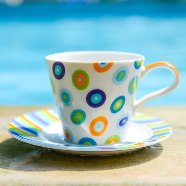 Bunte Tasse Kaffee am Pool