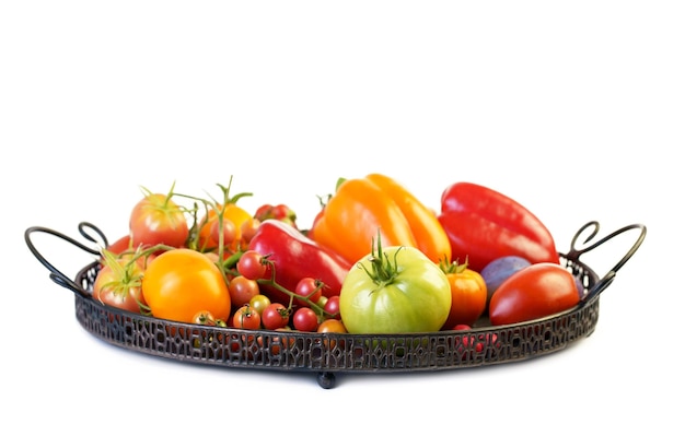 Bunte Tomaten verschiedener Größen und Arten in dunklem Holztablett über horizontaler Zusammensetzung der Draufsicht aus hellem Textil und rustikalem Holzhintergrund
