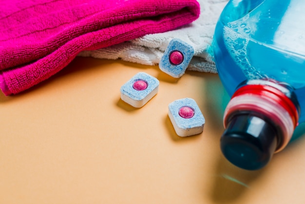 Foto bunte tücher und flüssiges reinigungsmittel mit geschirrspülmitteltabletten