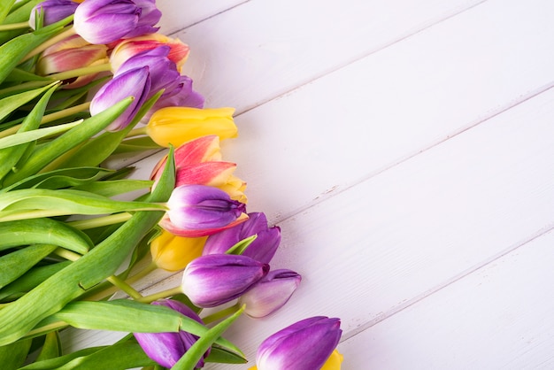 Bunte Tulpen auf einem Holztisch. Draufsicht mit Textfreiraum