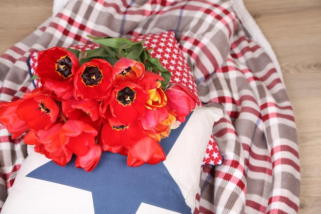 Bunte Tulpen mit Plaid und Kissen auf hellem Hintergrund