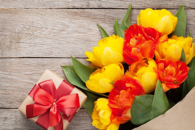 Bunte Tulpen und Geschenkbox auf Holztisch