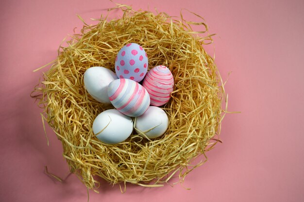 Bunte Vintage Ostereier im Nest auf rosa Hintergrund.