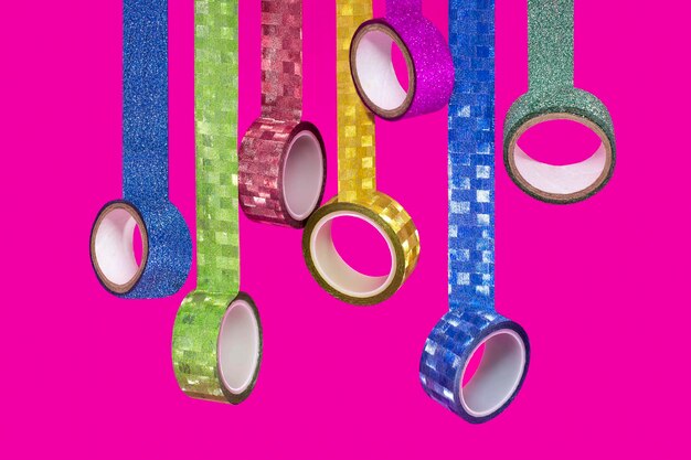 Bunte Washi Tapes hängen lose auf rosa Hintergrund
