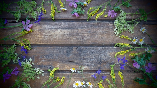 Bunte Wildblumen sind in einem Kreis auf einem Holztisch mit süßer Kamillennelke im Hintergrund angeordnet