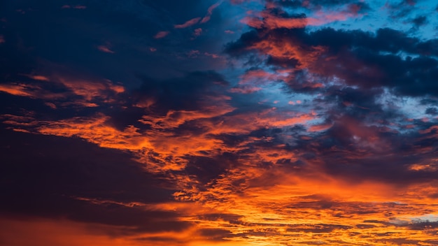 Bunte Wolken in der Dämmerung am Abend mit friedlichem Sonnenlicht nach Sonnenuntergang am dunkelblauen Himmel.