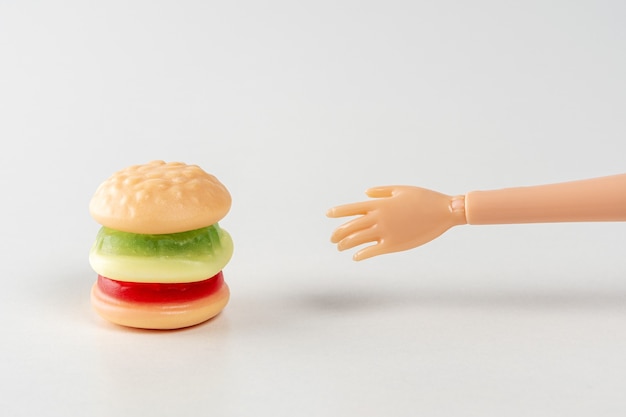 Bunter Bonbonhamburger mit einer Hand der Puppe.