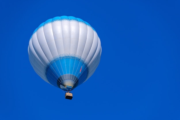 Bunter Heißluftballon, der gegen einen blauen Himmelhintergrund fliegt