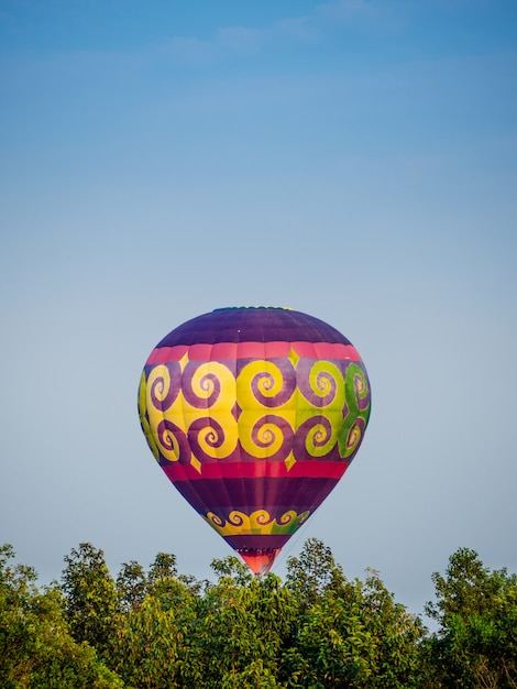 Bunter Heißluftballon, der über blauen Himmel fliegt