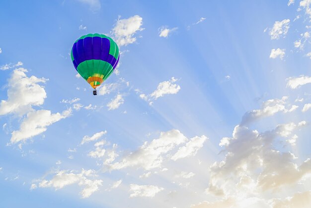 Bunter Heißluftballon, der über blauen Himmel mit weißen Wolken fliegt.