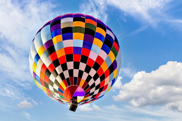 Bunter Heißluftballon, der über blauen Himmel mit weißen Wolken fliegt