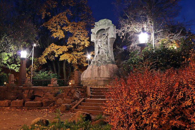 Bunter Herbstpark bei Nacht mit Laternen und einer Skulptur